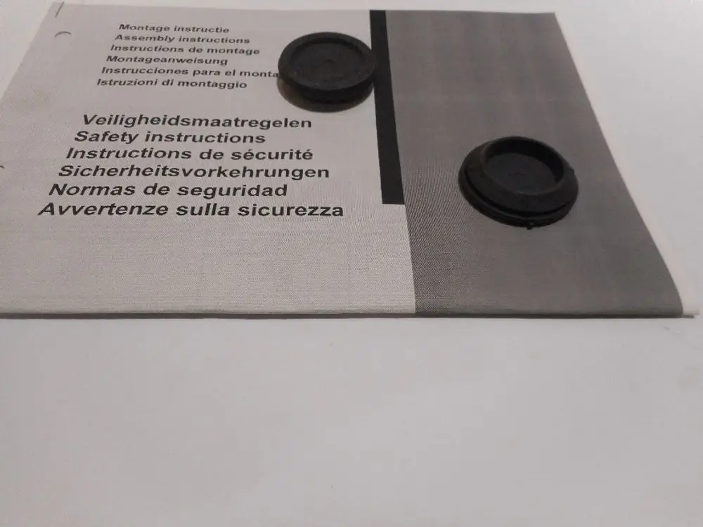 Zwei schwarze Kunststofftulen liegen auf einem Handbuch für Montage- und Sicherheitsanweisungen von Remeha. Die Anleitung ist mehrsprachig und enthält Sicherheitsinformationen.